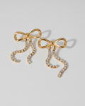Gold bow-shaped earrings with rhinestones on a white background